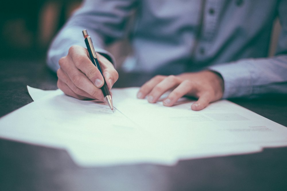 A hand signing a printed letter