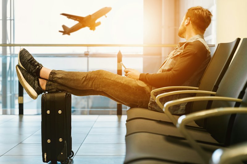 A traveller waiting at an airport gate with a suitcase