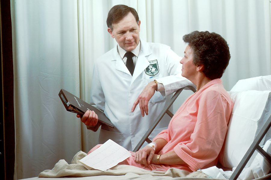 A doctor talking with a patient sitting up in a hospital bed